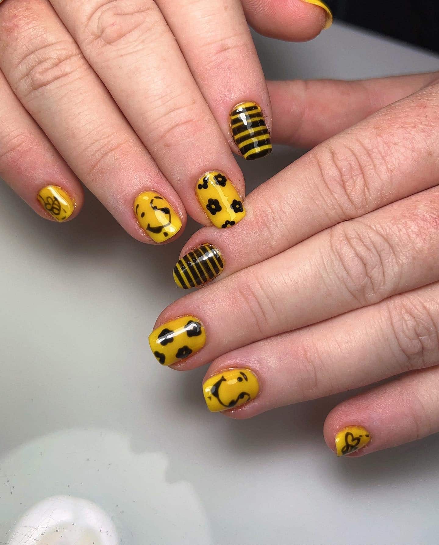 11. Striped Bee Vibes with Smiley Accents - bee nail ideas