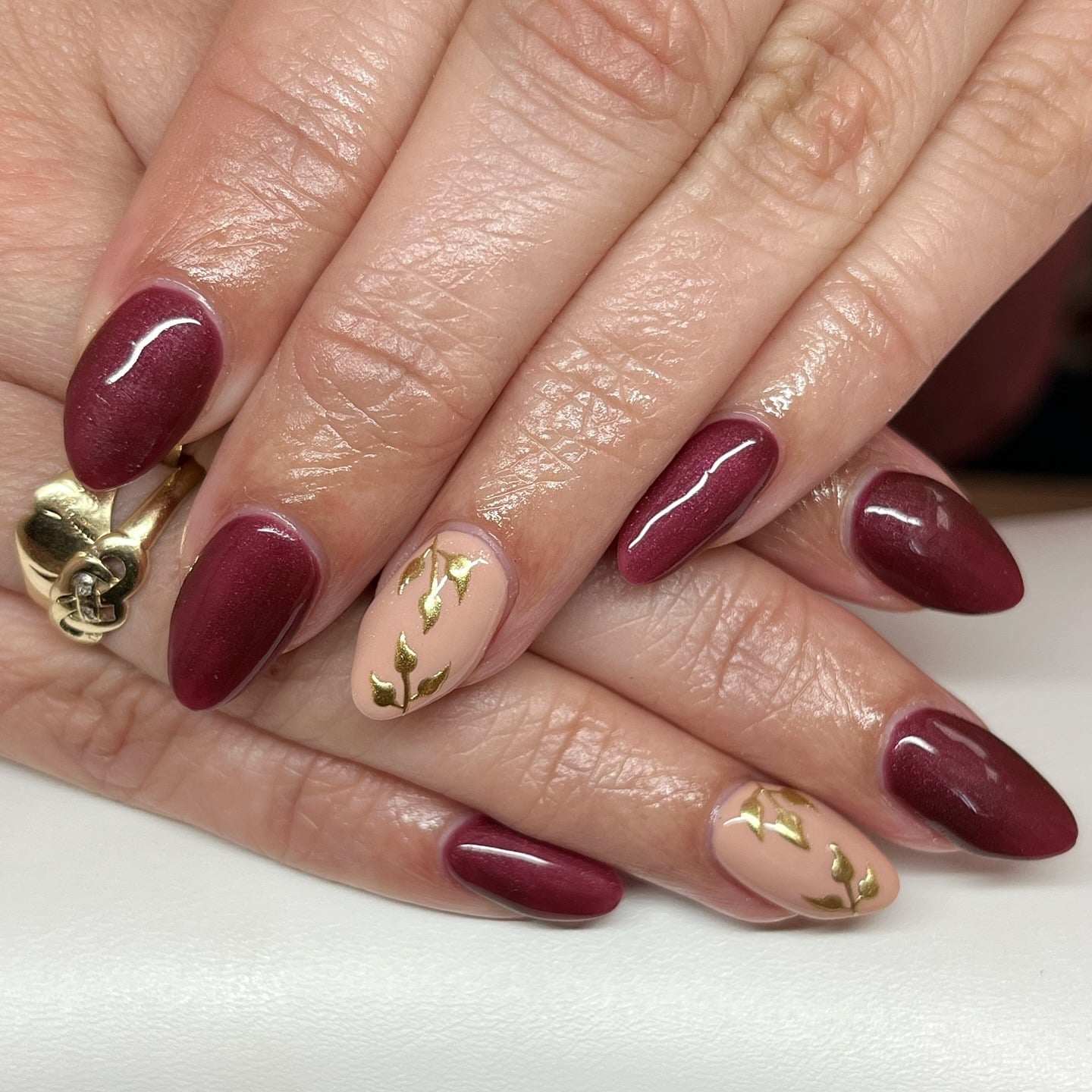 21. Burgundy Almond Nails with Golden Leaf Accents - burgundy and gold nail ideas