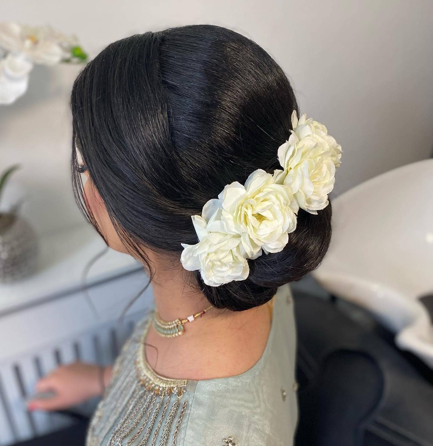 14. Polished Bun with Floral Accents in Jet Black - Sleek Hairstyles