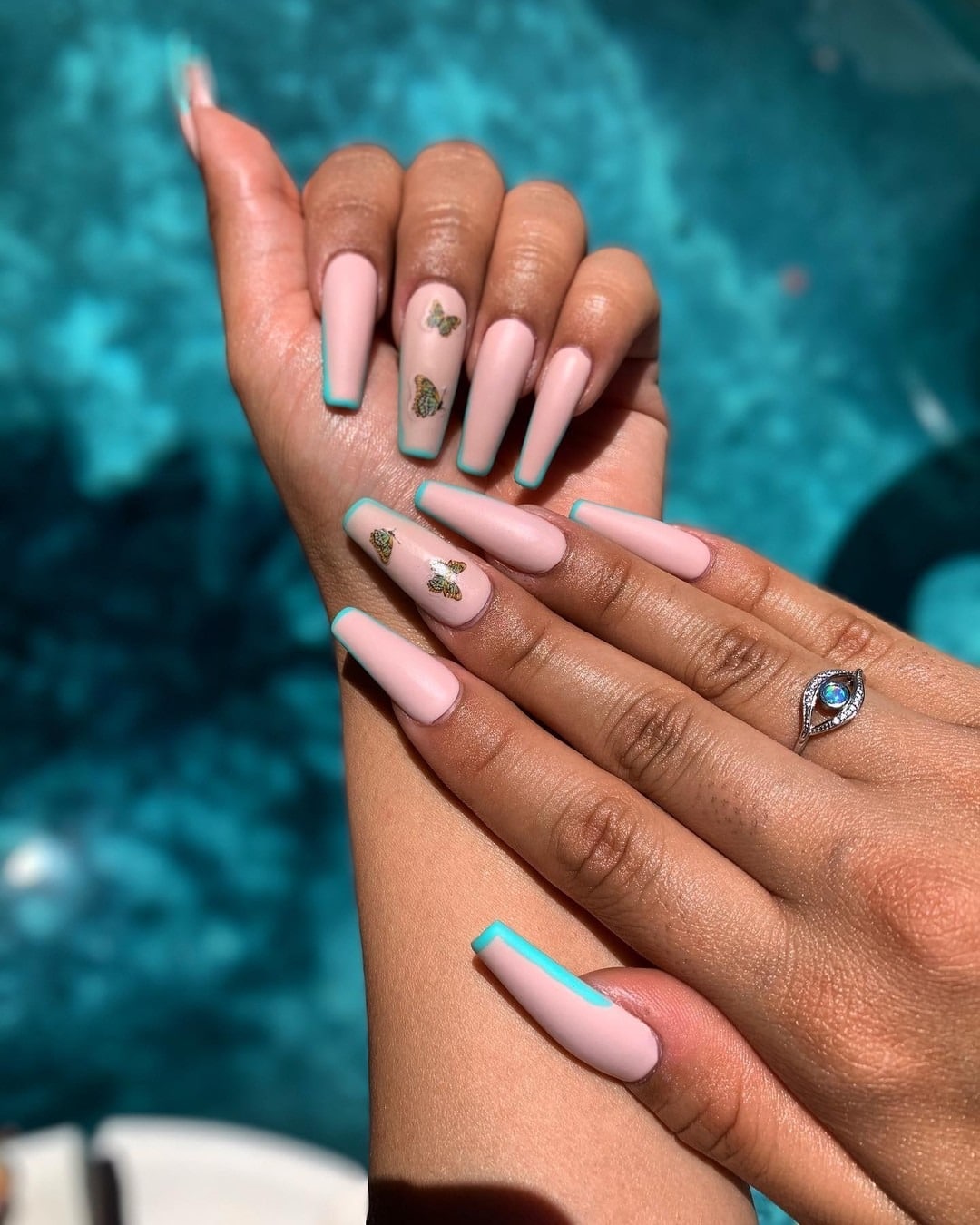 13. Pastel Nude with Aqua Edge and Butterfly Charms - long coffin nail ideas