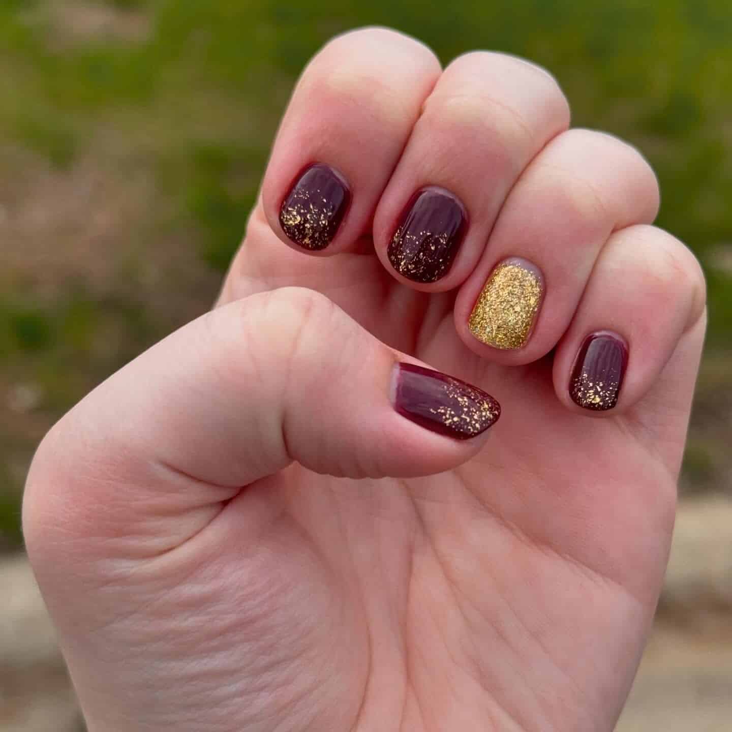 17. Gilded Spark Fade - maroon and gold nail ideas