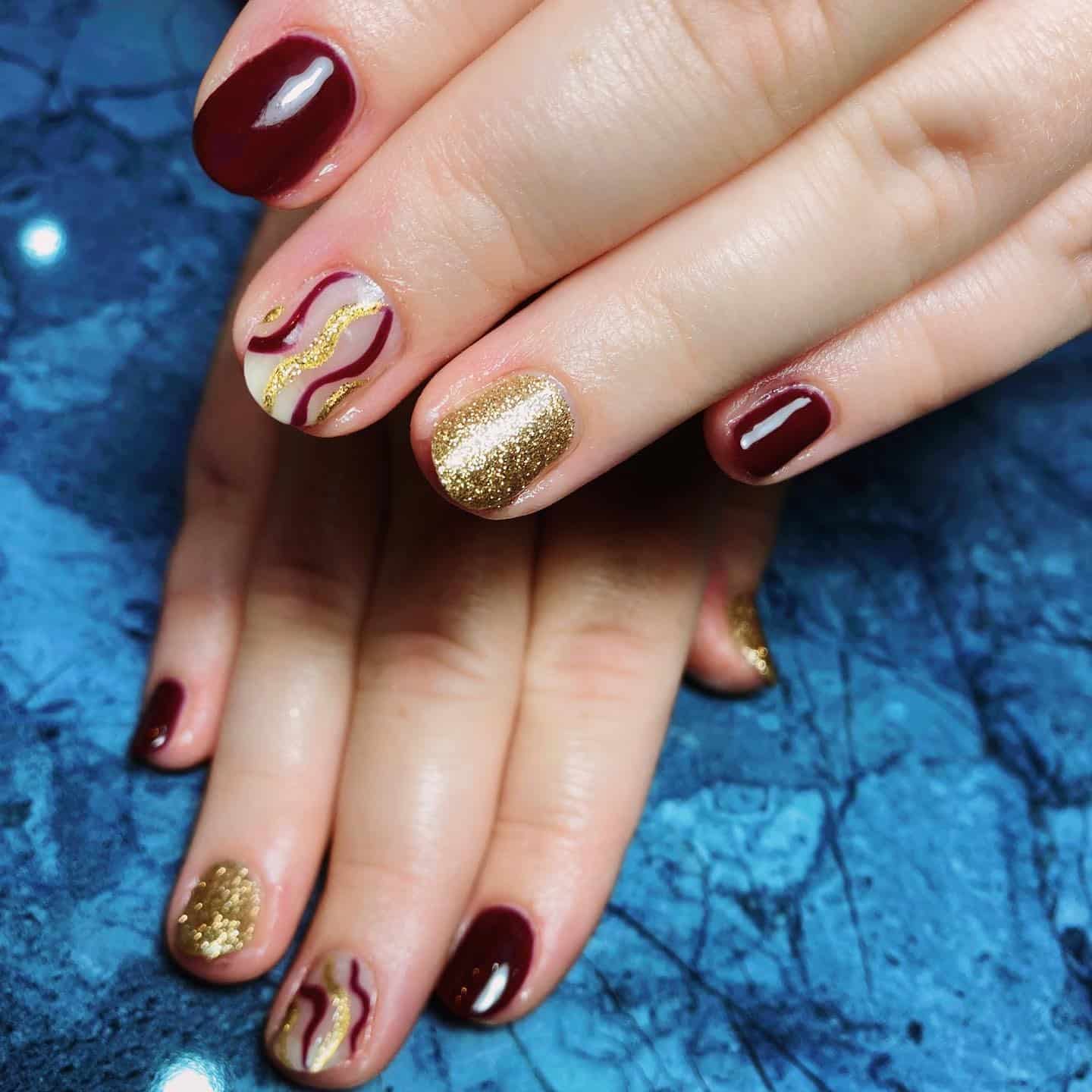 20. Artistic Waves in Burgundy and Gold - maroon and gold nail ideas