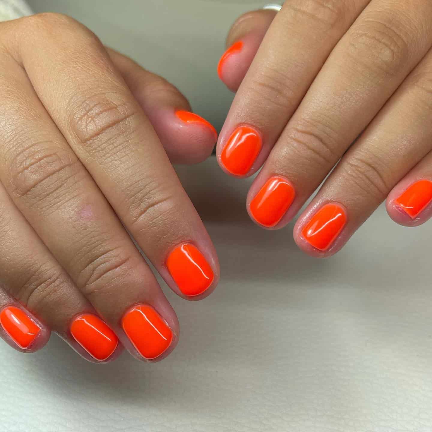4. Short and Sleek Neon Pop - neon orange nail ideas