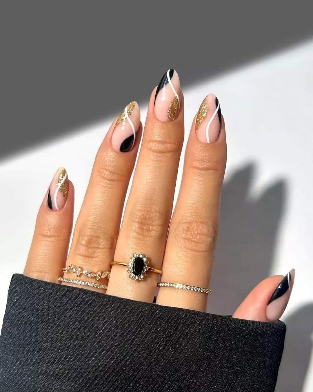 13. Midnight Swirl – Abstract Gold and Black Almond Nails - new years eve nail ideas