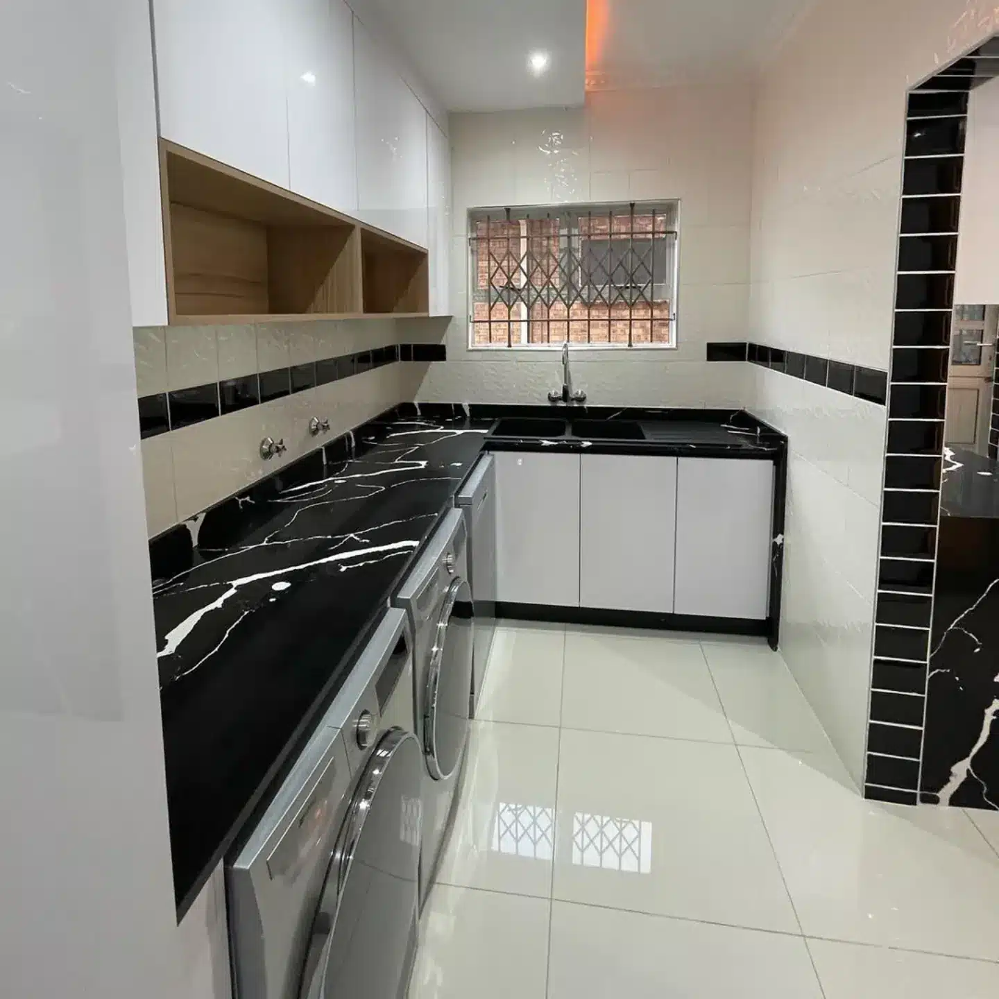 7. Compact Chic with Black Veined Counters - white kitchen floor ideas