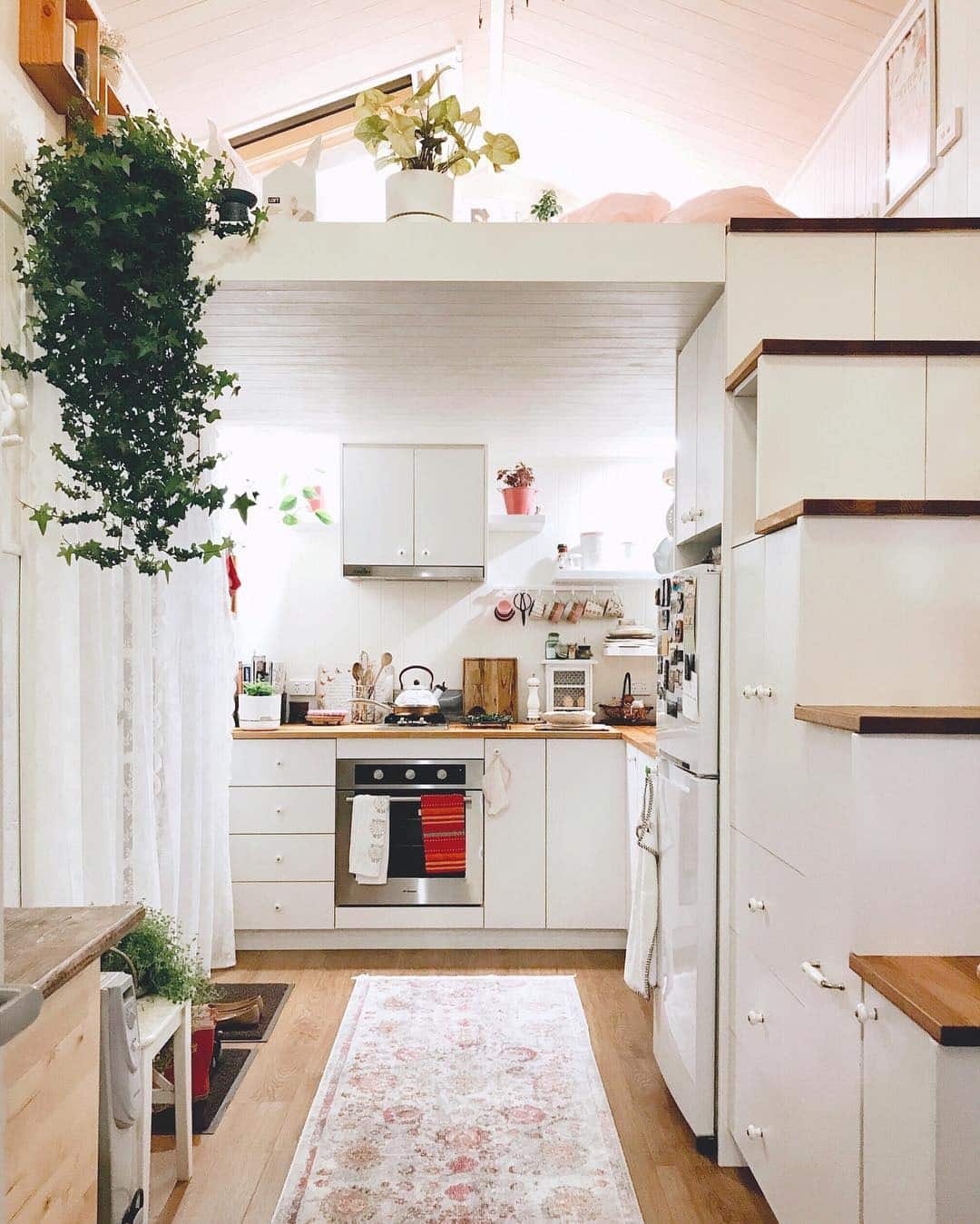 6. Soft White Kitchen With Warm Wood and Loft Storage - tiny house kitchen ideas