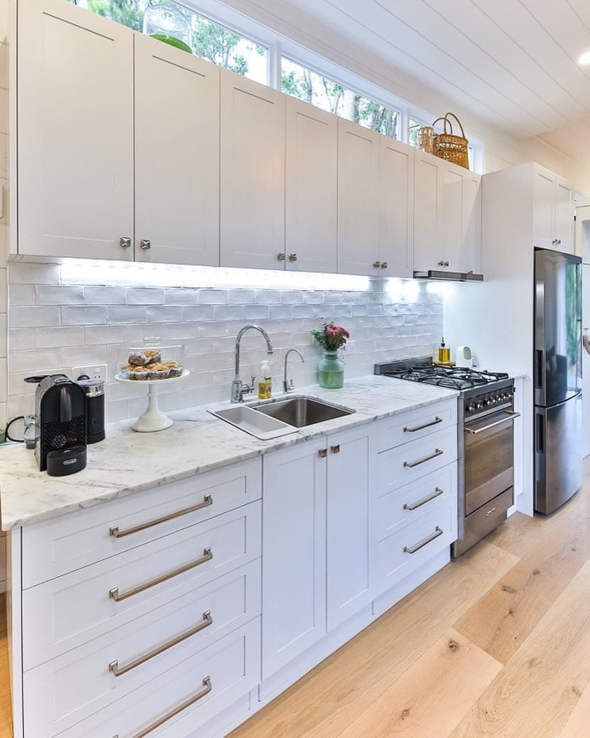 22. Bright White Cottage Kitchen With Marble Counters - tiny house kitchen ideas