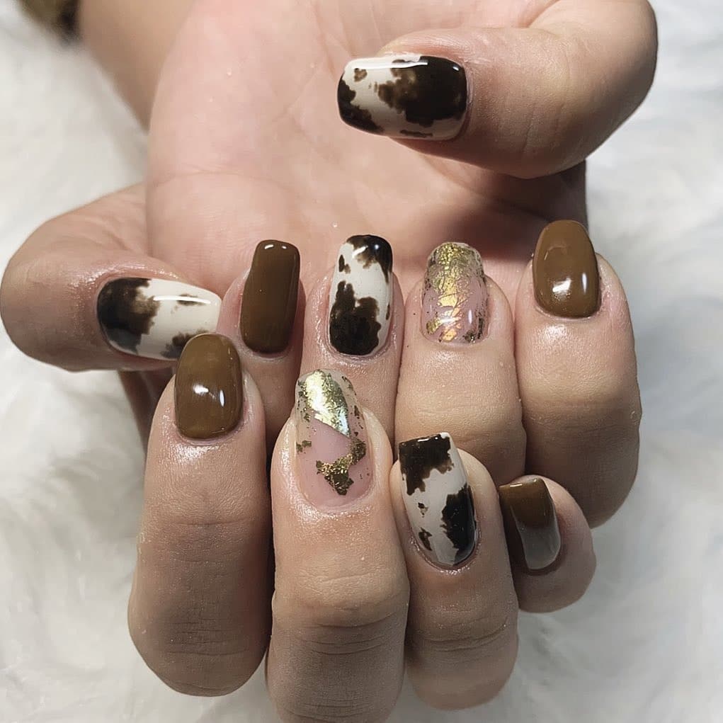 15. Chocolate Swirl Cow Print With Gold Foil - animal nail ideas