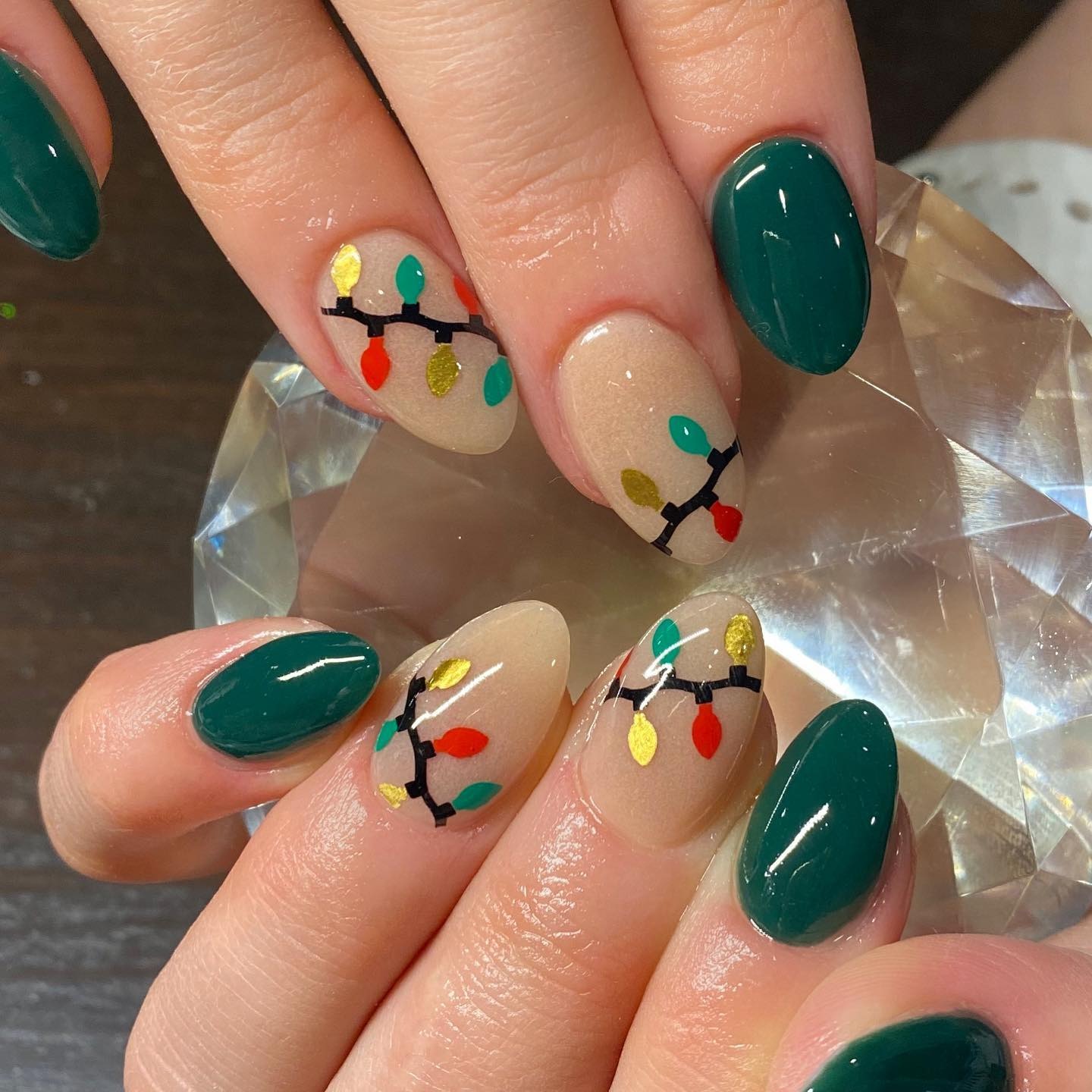 13. Emerald Green and Gold-Toned Lights on Nude Almond Nails - christmas lights nail ideas