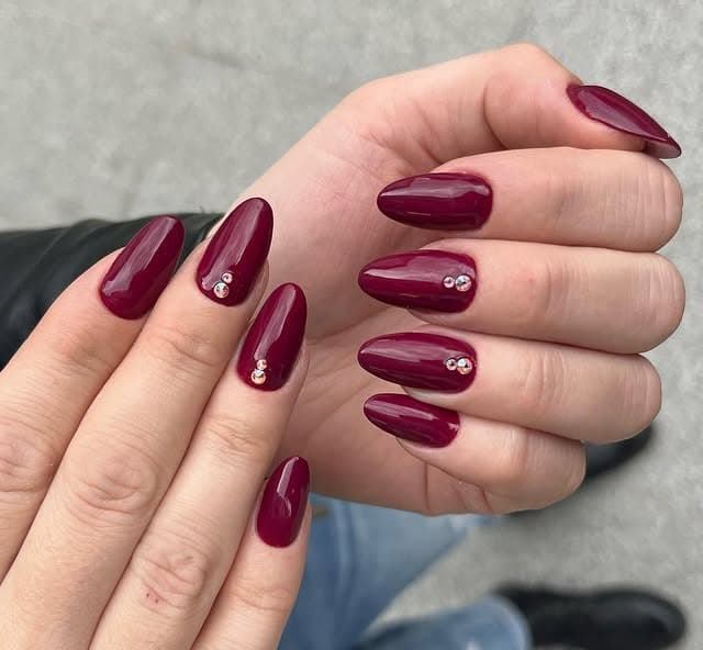 1. Garnet Gloss Almond Nails with Crystal Accents - dark color nail ideas