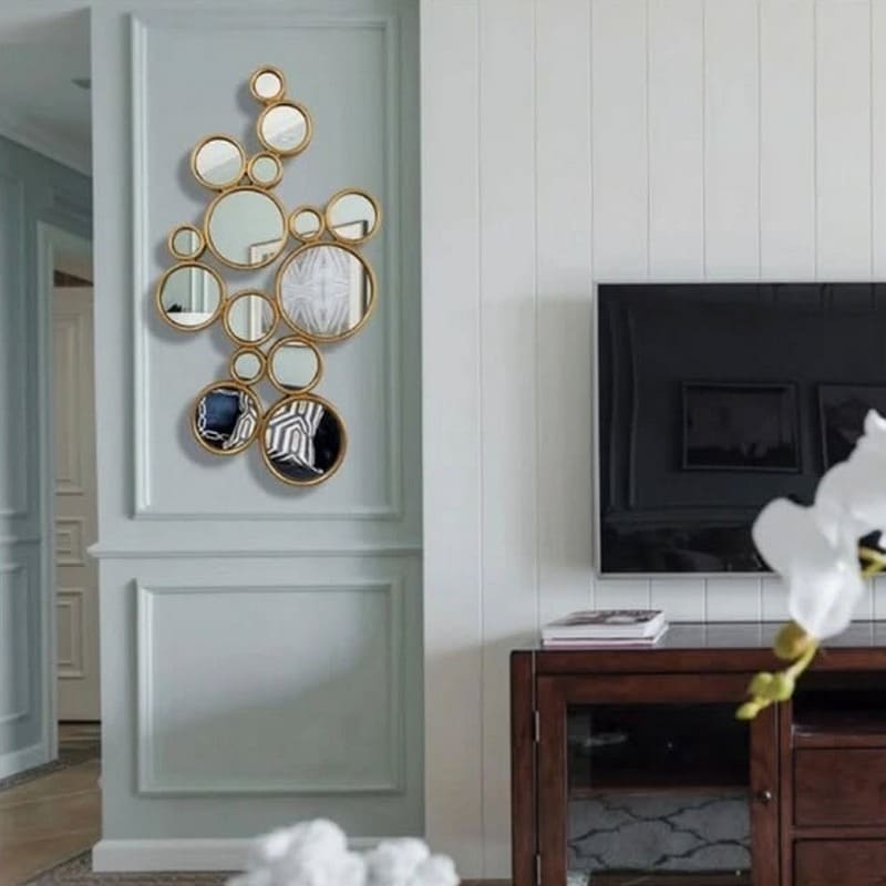 6. Clustered Round Mirrors in Brushed Gold on Pale Blue Paneling - mirrors in living room ideas