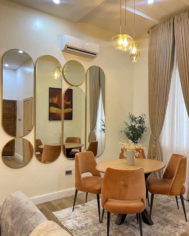 10. Elongated Gold-Framed Mirror Set in Warm Neutral Dining Space - mirrors in living room ideas