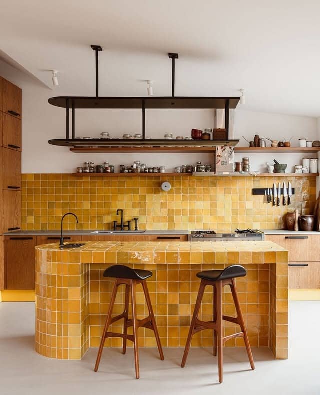 9. Golden Tiled Kitchen With Sculptural Island and Wood Accents - yellow kitchen ideas