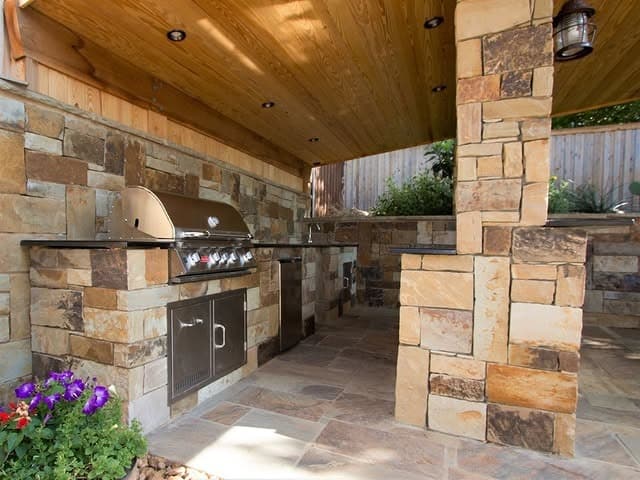 14. Rustic Pavilion Kitchen with Beige Stone and Honey Wood - rustic outdoor kitchen ideas