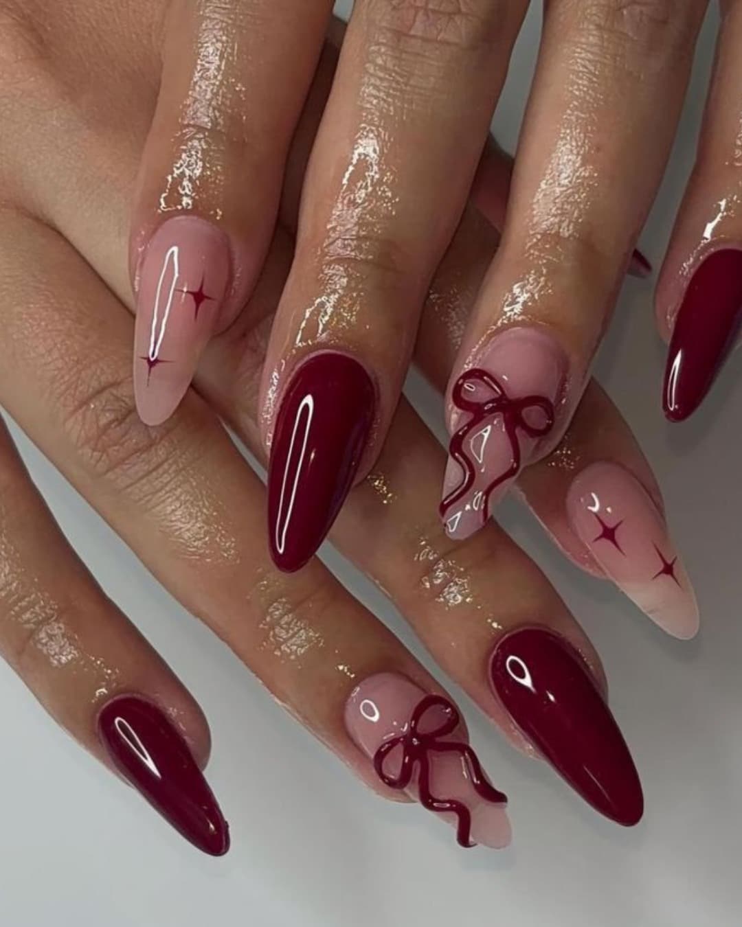 21. Burgundy Almond Nails with Bow and Star Accents - long red nail ideas