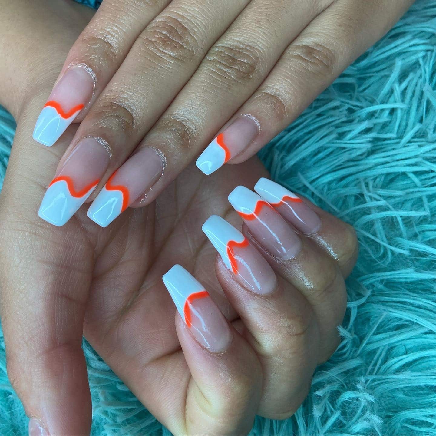 2. White French Tips with Orange Wave Accents - orange and white nail ideas