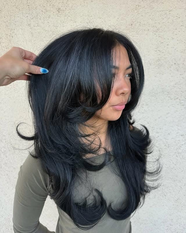 2. Voluminous Feathered Layers with Face-Framing Bangs in Jet Black - Long Layered Hairstyles with Bangs