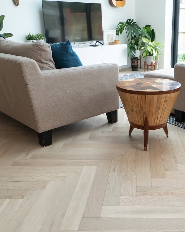 19. Pale Herringbone Wood Flooring with Modern Comfort - living room floor ideas