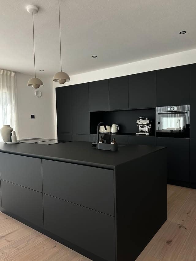 22. Minimal Black Kitchen with Oversized Island - black kitchen ideas