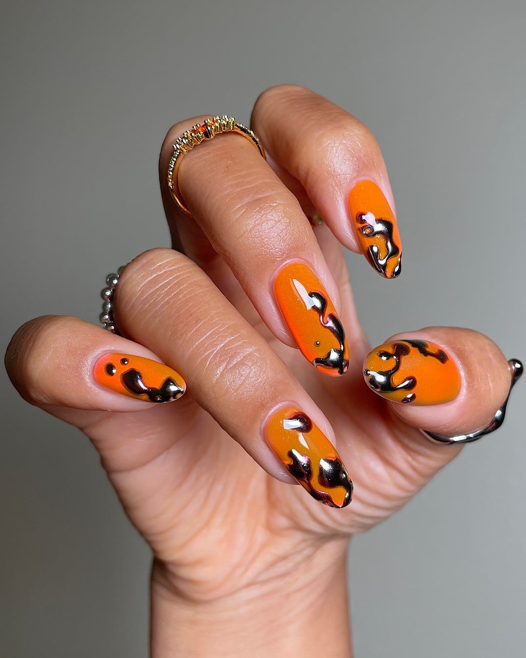 19. Black Chrome Drip Orange Almond Nails - black and orange nail ideas