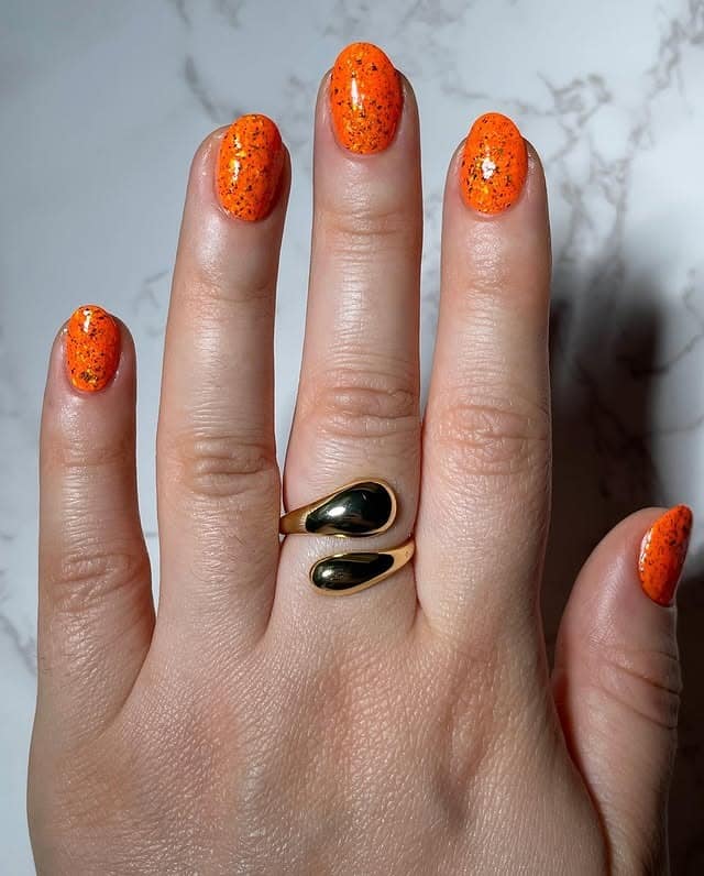 7. Speckled Orange Oval Nails with Glitter Detail - bright orange nail ideas