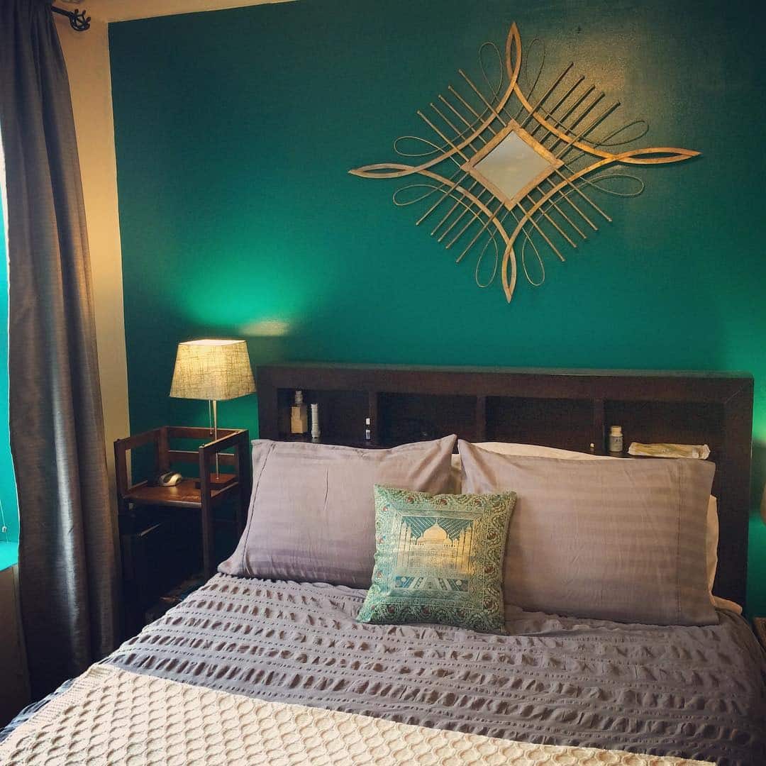 8. Moody Turquoise Feature Wall with Warm Lighting - turquoise bedroom ideas