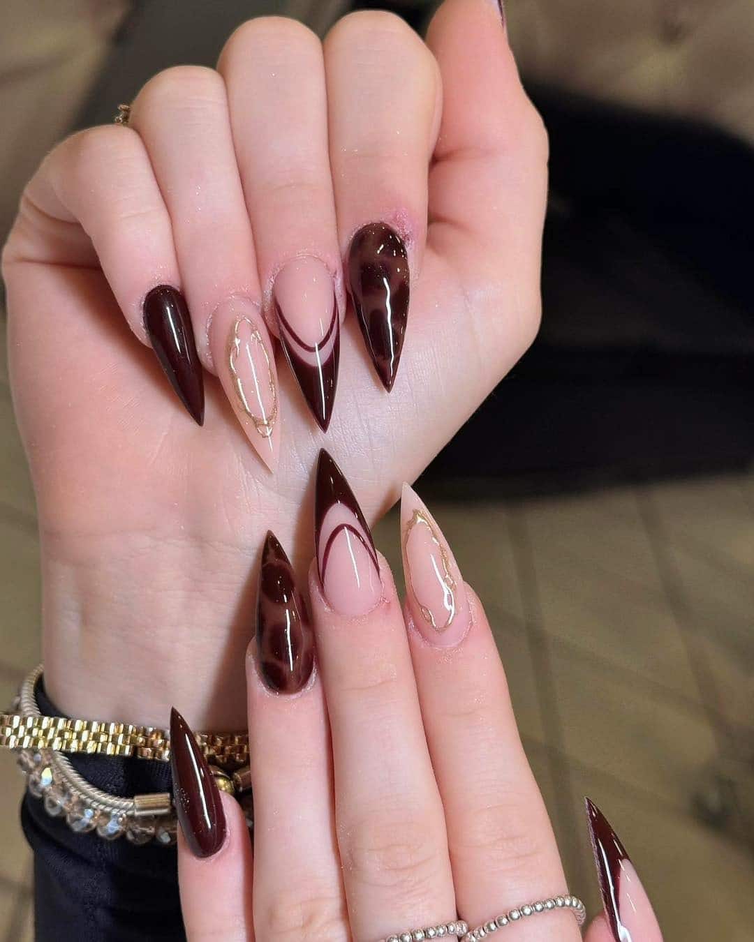 7. Chocolate Burgundy Stiletto Nails with Nude Negative Space & Gold Foil - burgundy and gold nail ideas