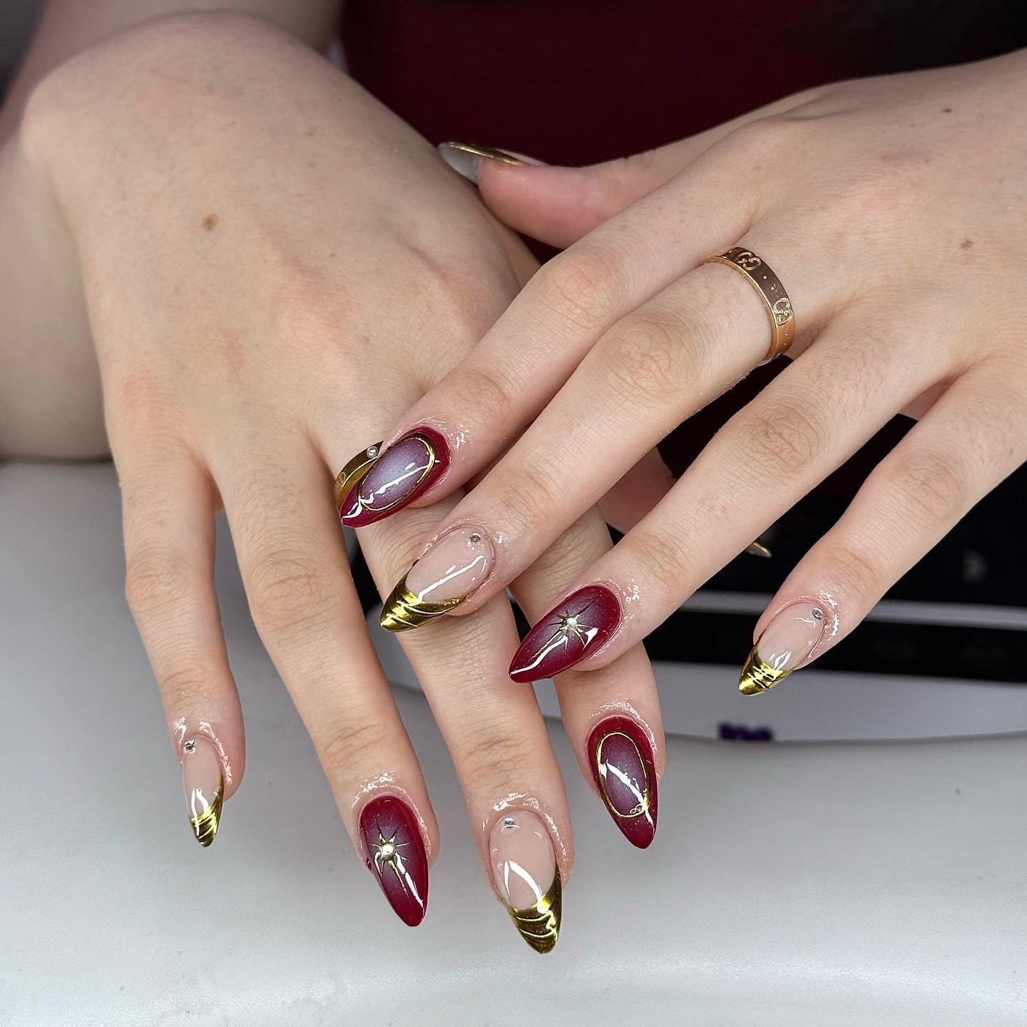 10. Burgundy Almond Nails with Gold Chrome Tips & Starburst Accents - burgundy and gold nail ideas