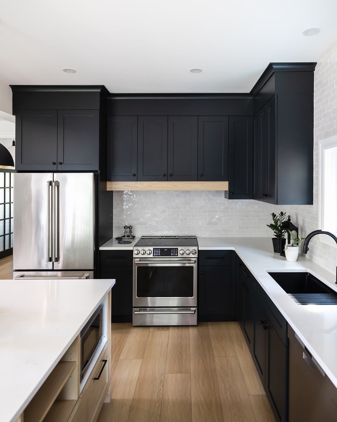 22. Matte Black Cabinets with White Subway Tile and Light Wood Floors - black cabinets kitchen ideas
