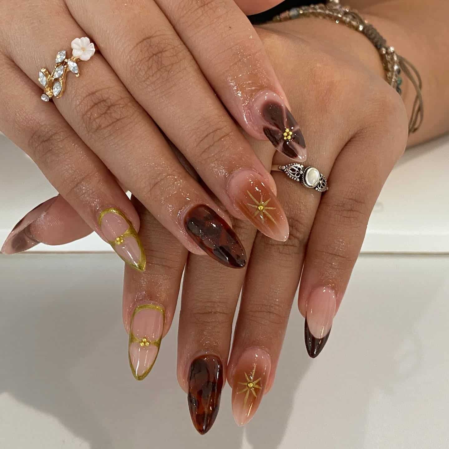 3. Tortoiseshell Almond Nails with Gold Starburst Details - gold and brown nail ideas