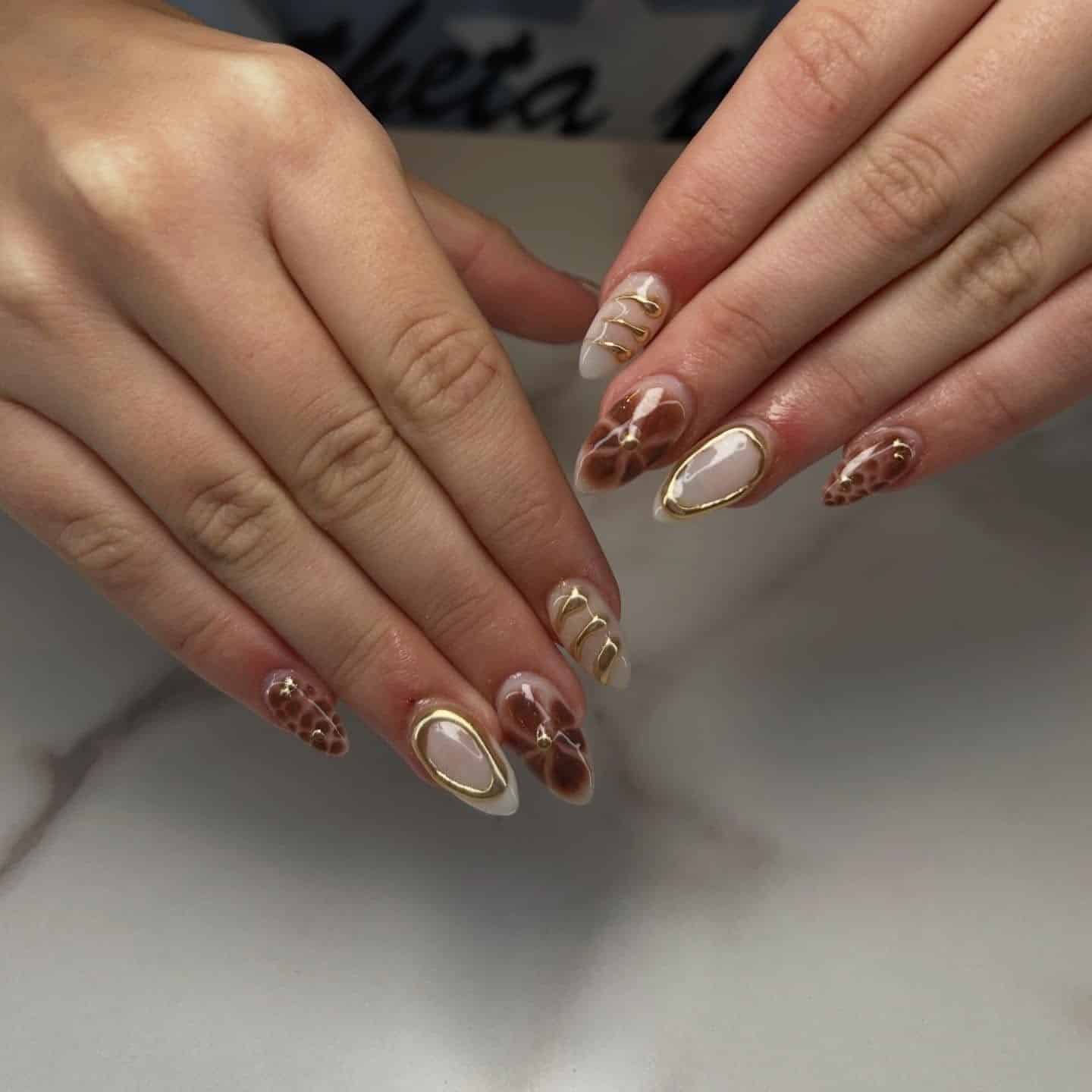 7. Neutral Nude and Brown Floral Almond Nails with Gold Outlines - gold and brown nail ideas