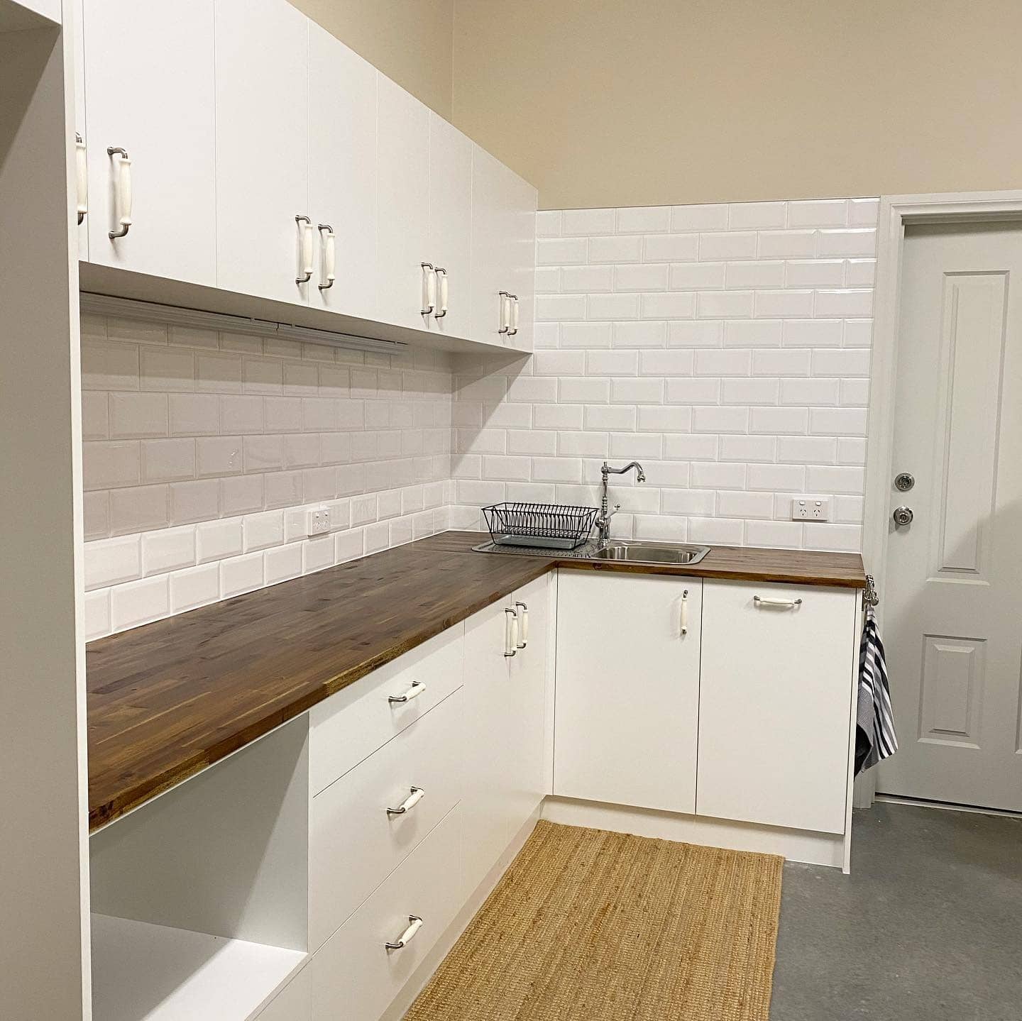 12. Minimal White Garage Kitchen with Walnut Countertops - garage kitchen ideas