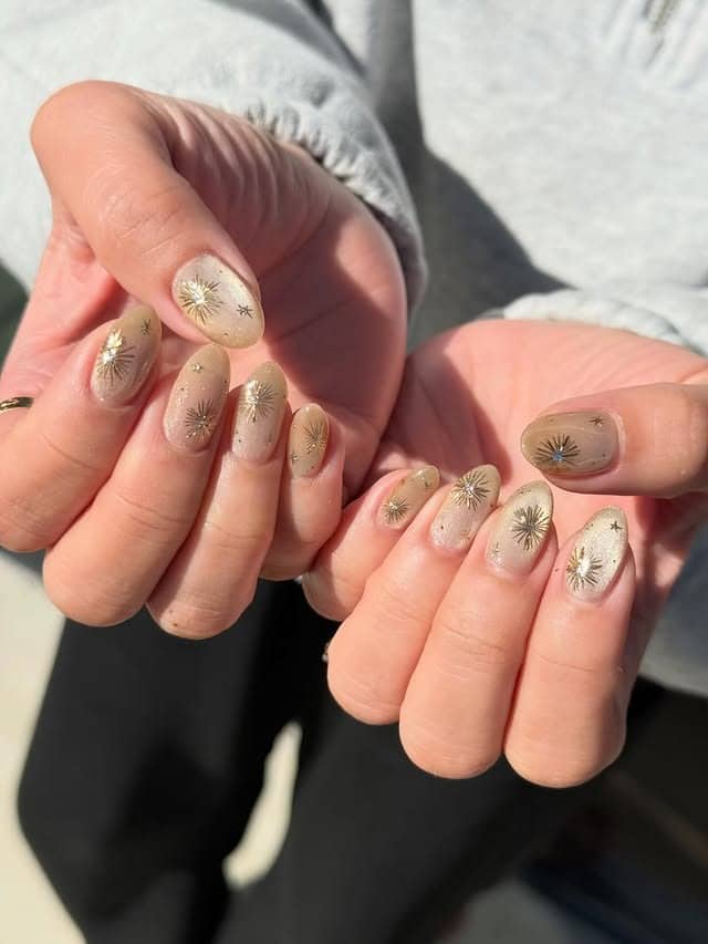 11. Champagne Almond Nails with Gold Chrome Starbursts - gold chrome nail ideas
