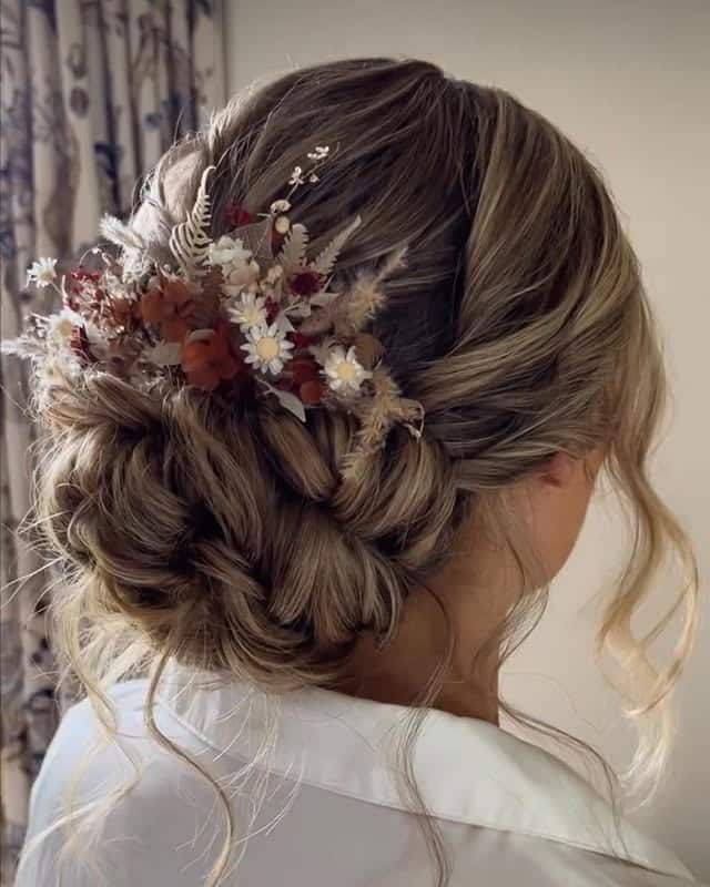 2. Textured Low Chignon with Warm Bronde and Floral Accents - Bridesmaid Hairstyles