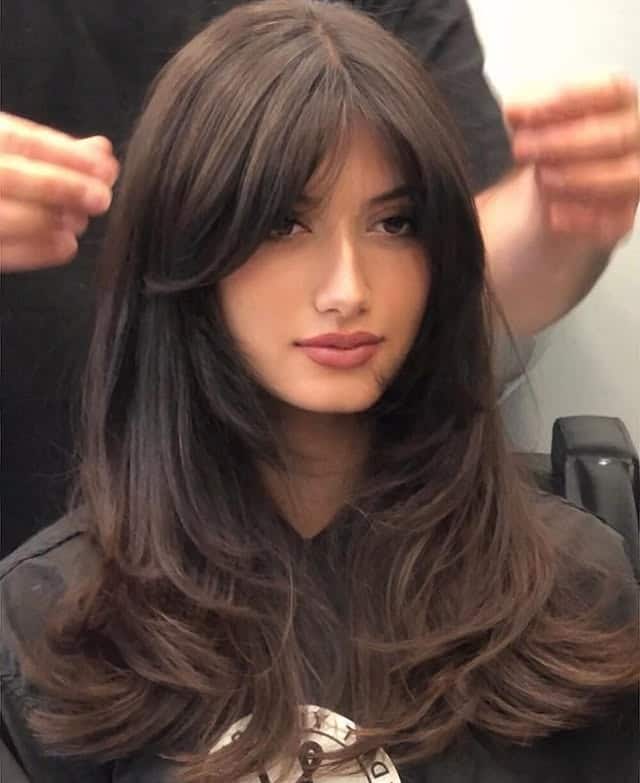 22. Voluminous Medium Layers with Deep Chocolate Curtain Bangs - Medium Haircuts With Bangs