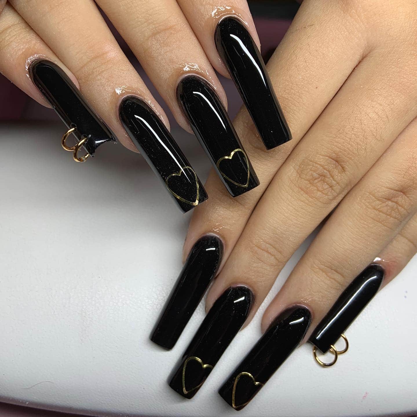 10. Glossy Black Coffin Nails with Gold Heart Accents - long black nail ideas