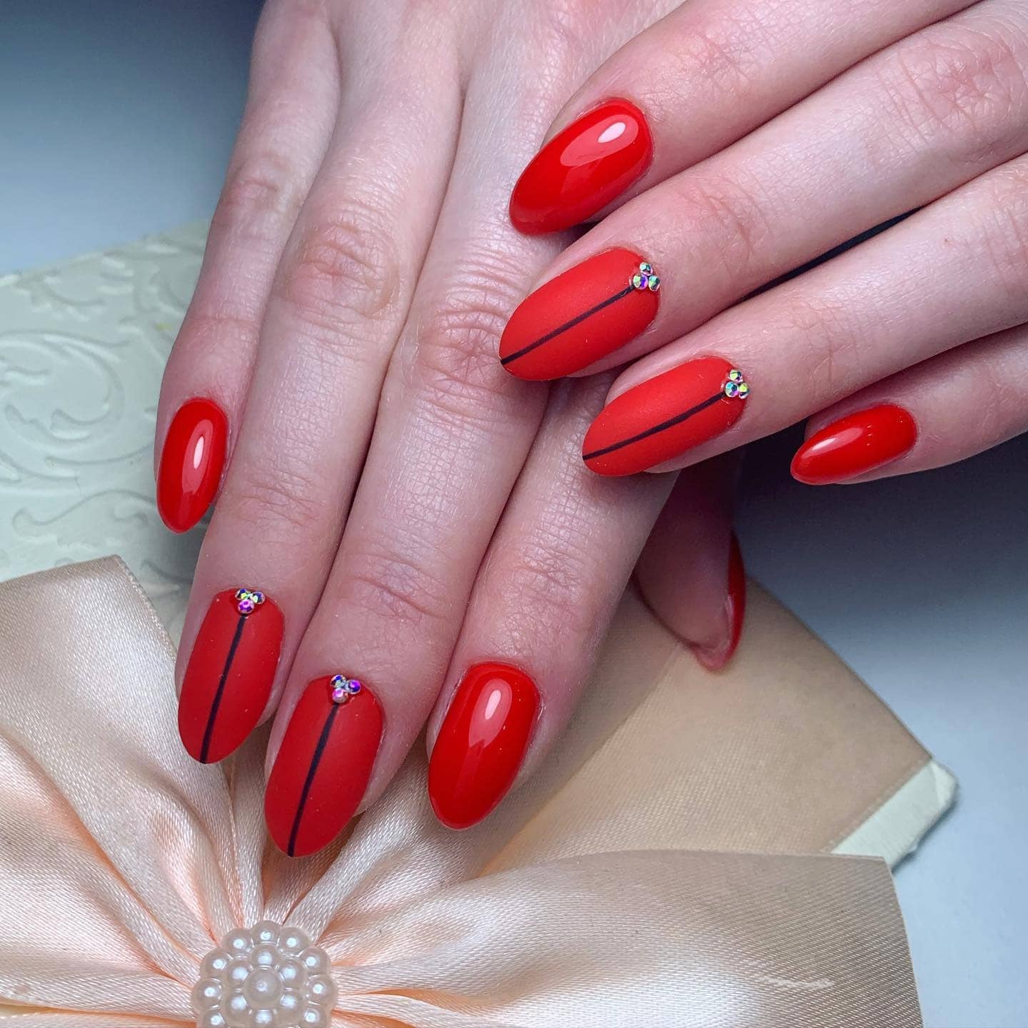 13. Matte Red Almond Nails with Black Line and Rhinestone Accent - matte red nail ideas