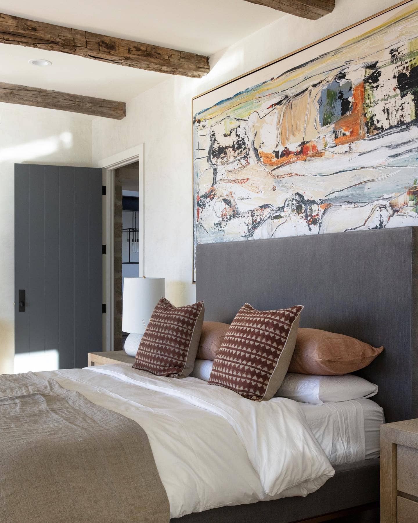 21. Rustic Neutral Bedroom with Warm Wood Beams and Abstract Art - serene bedroom ideas