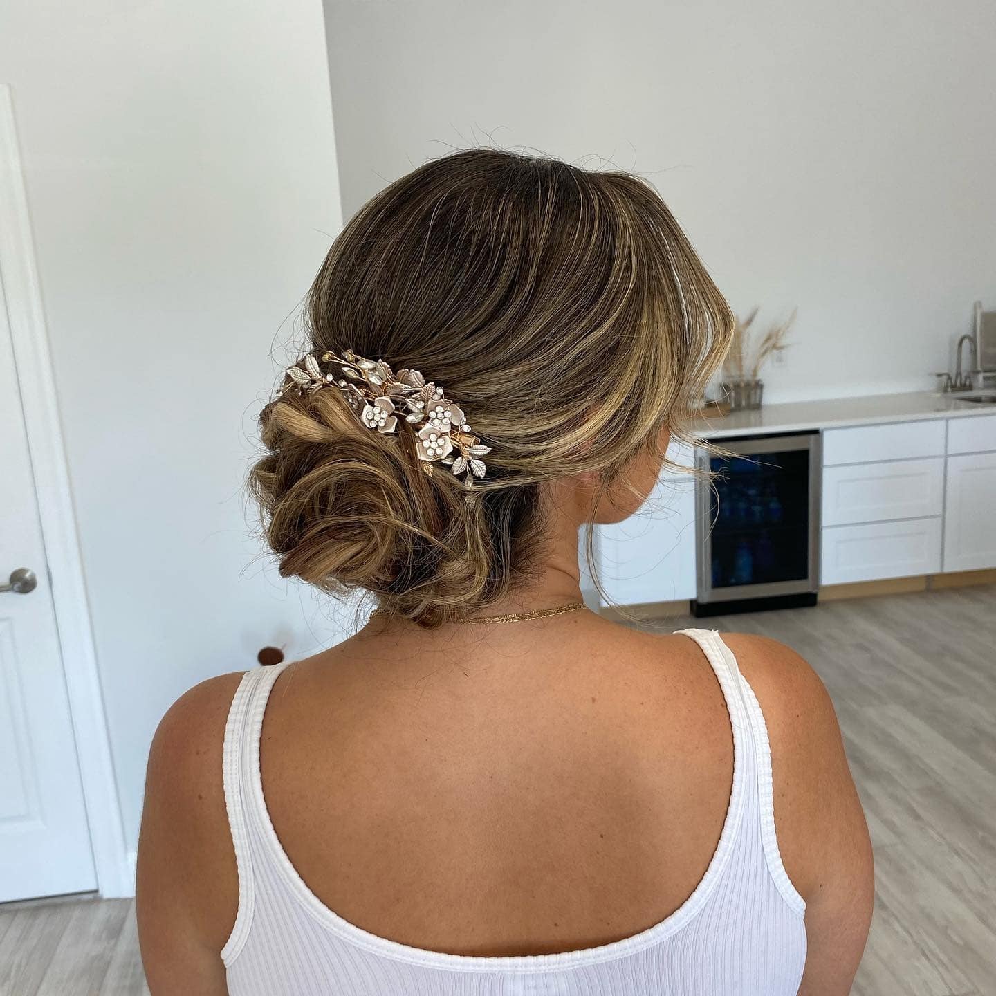 20. Honey Blonde Textured Low Bun with Floral Hairpiece - Elegant Hairstyles