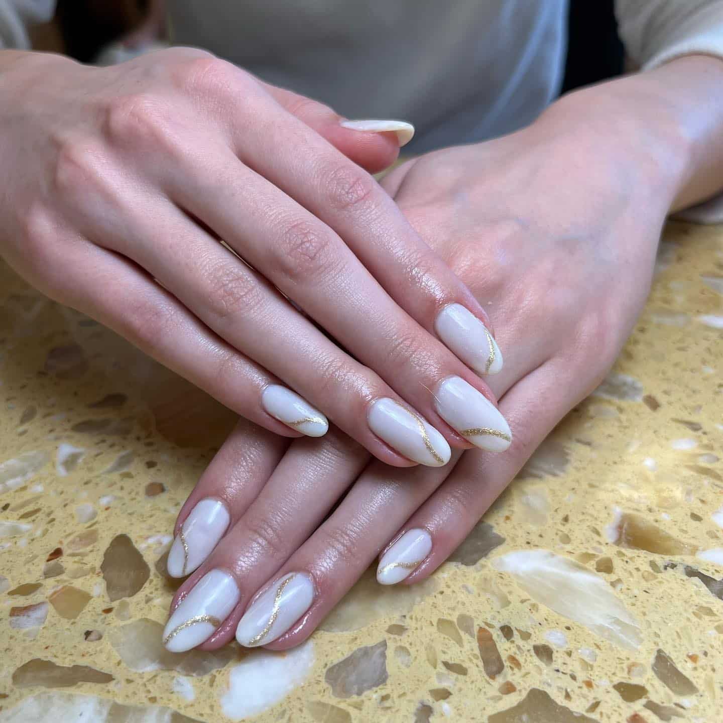7. Off White Almond Nails with Minimal Gold Wave Detailing - off white nail ideas
