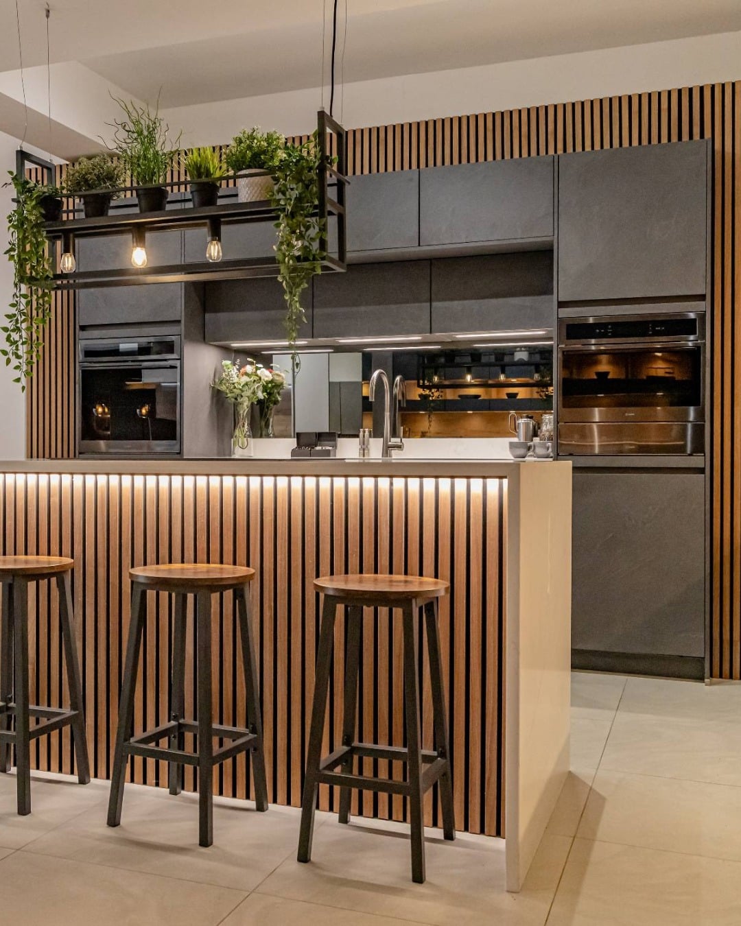 18. Slatted Wood Industrial Kitchen with Black Cabinets and Floating Plant Rack - industrial kitchen ideas