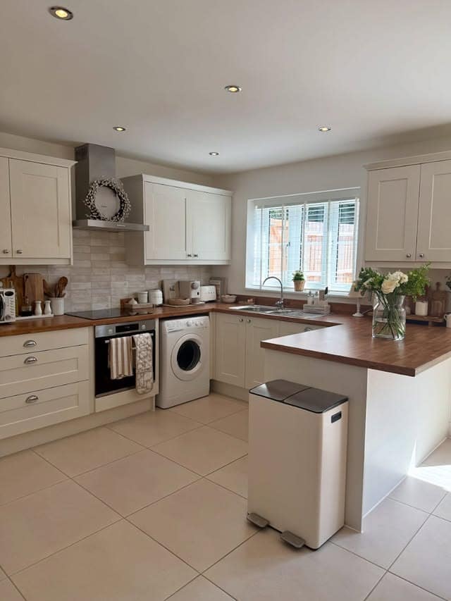 14. Modern Cream Kitchen With Wood Worktops and Neutral Tile Flooring - cream kitchen ideas