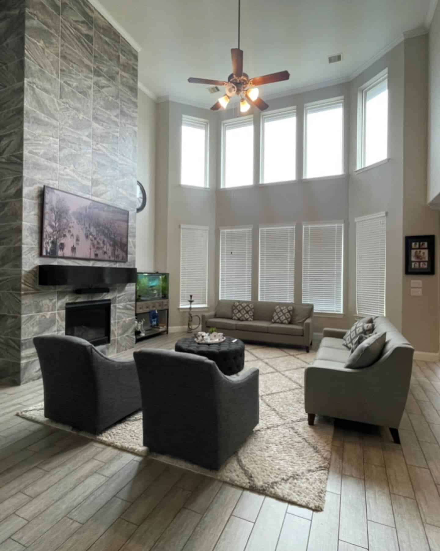 16. Double-Height Light Gray Living Room with Stone Fireplace - light gray living room ideas