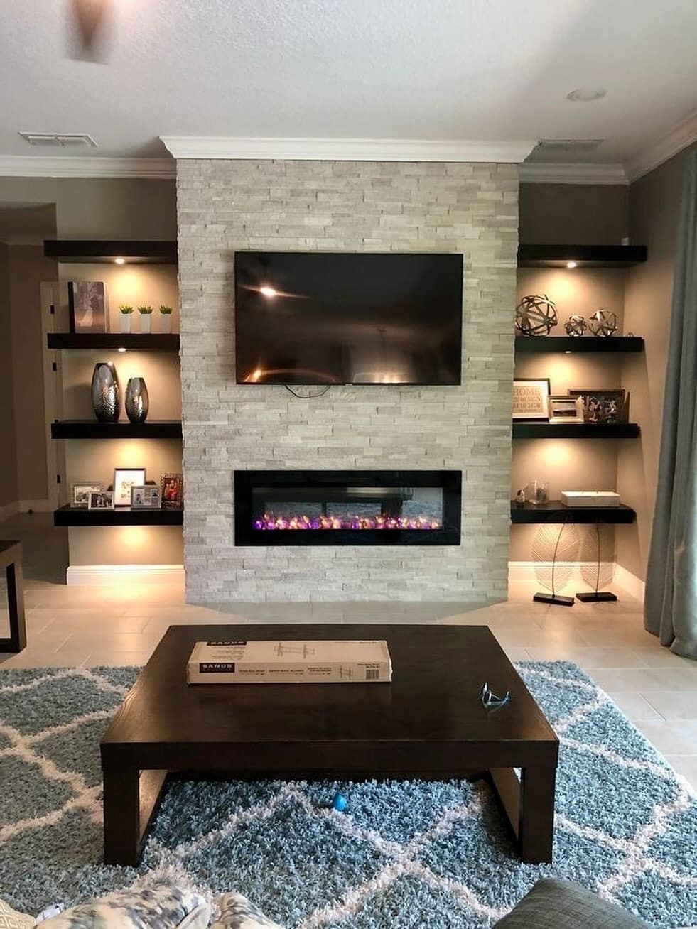 14. Modern Stone Fireplace Living Room with Floating Shelves and Accent Lighting - living room ideas with fireplace