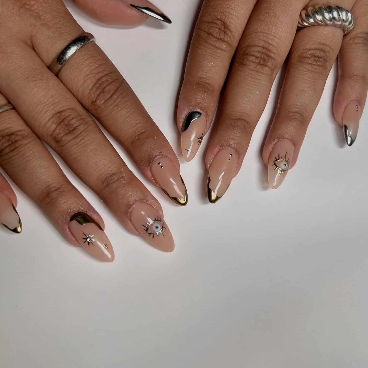 22. Nude Almond Nails with Gold Chrome Accents and Eye Art - silver and gold nail ideas