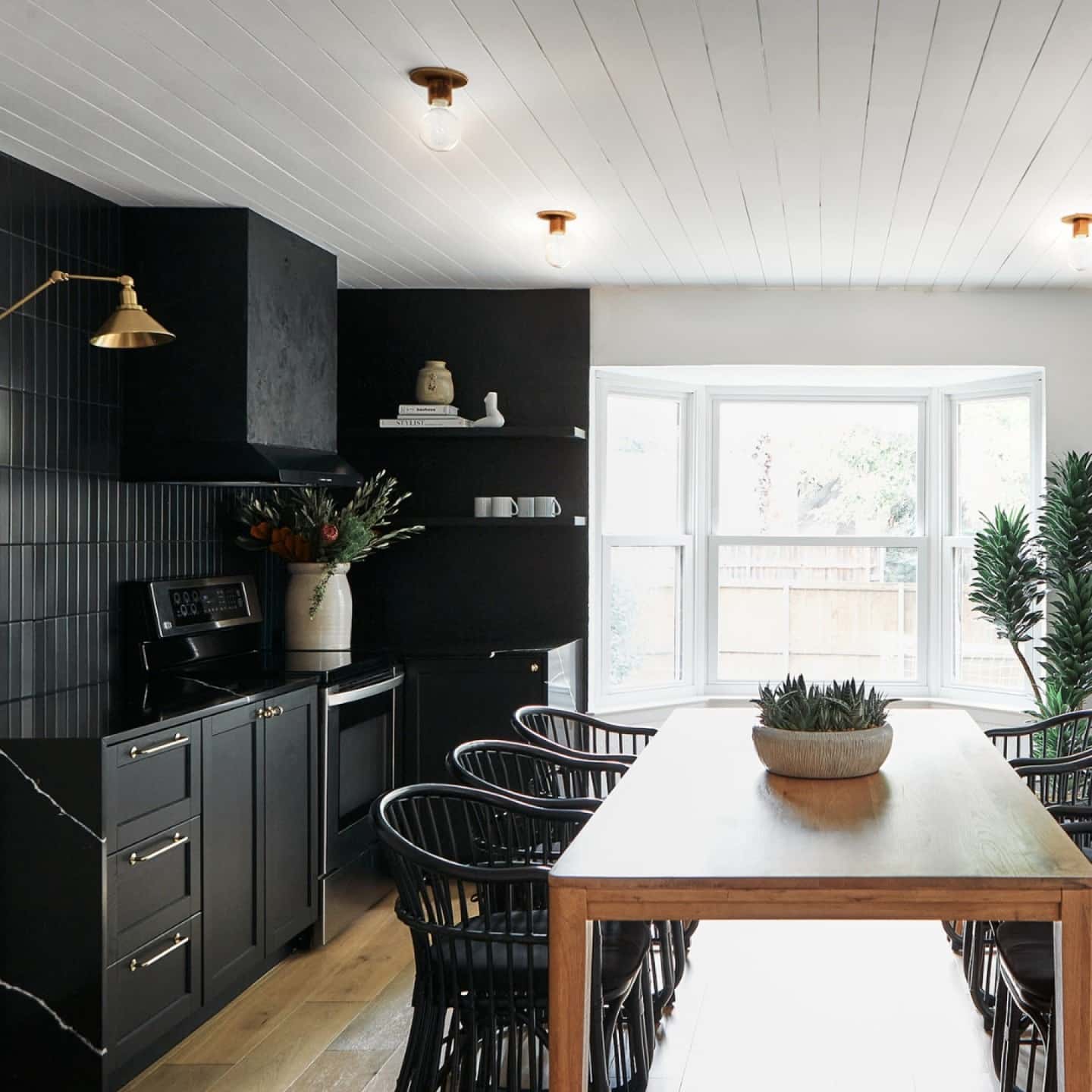 8. Moody Black Kitchen with Natural Wood Dining Elements - black and white kitchen ideas