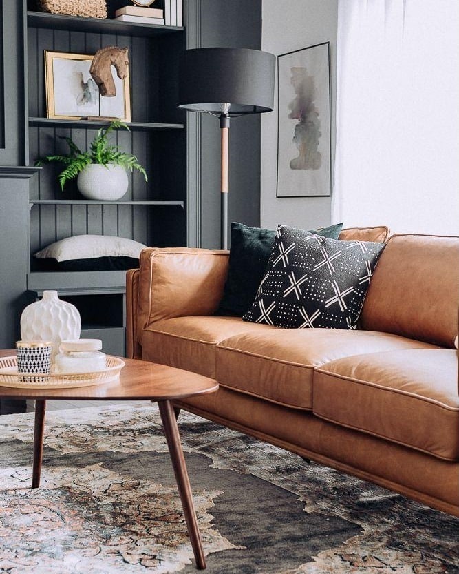 11. Warm Tan Leather Sofa with Charcoal Accents and Built-In Shelving - dark brown sofa living room ideas