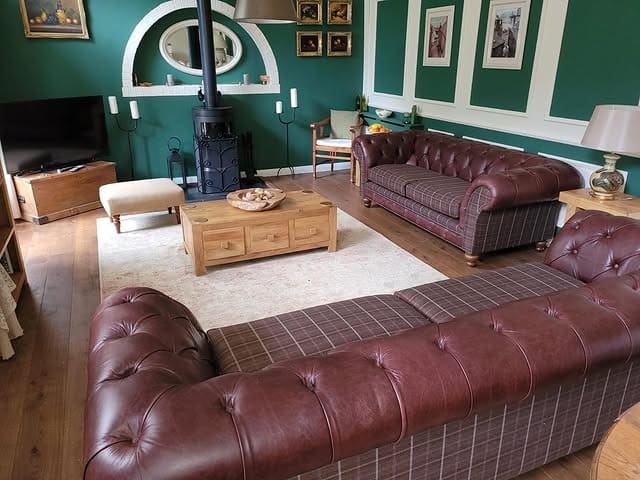 14. Deep Brown Chesterfield Sofa with Classic Green Wall Paneling - dark brown sofa living room ideas