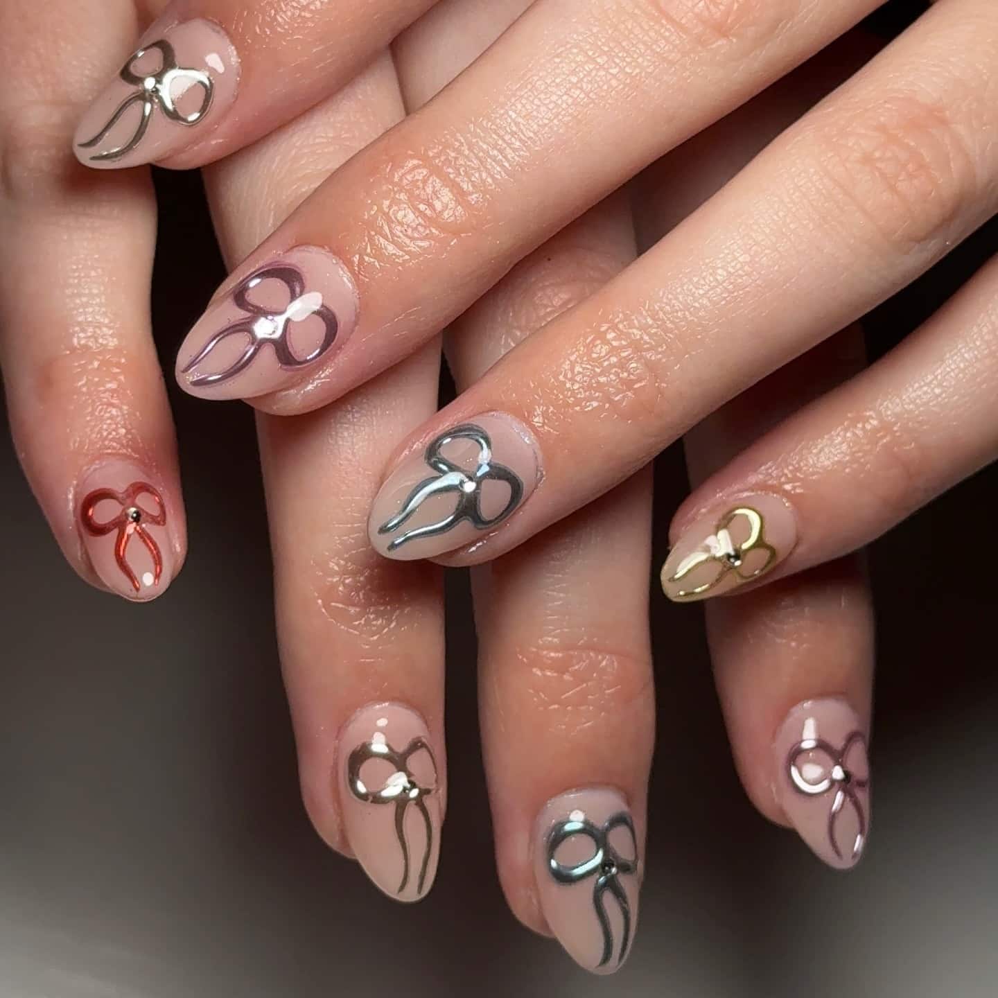 14. Glossy Nude Almond Nails with Chrome Bow Accents - nail ideas with bows