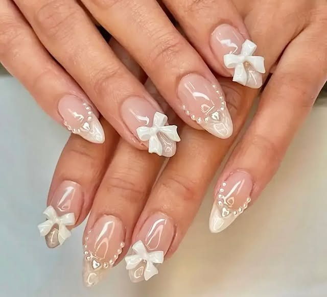 20. Milky Nude Almond Nails with White 3D Bows and Pearl Details - nail ideas with bows